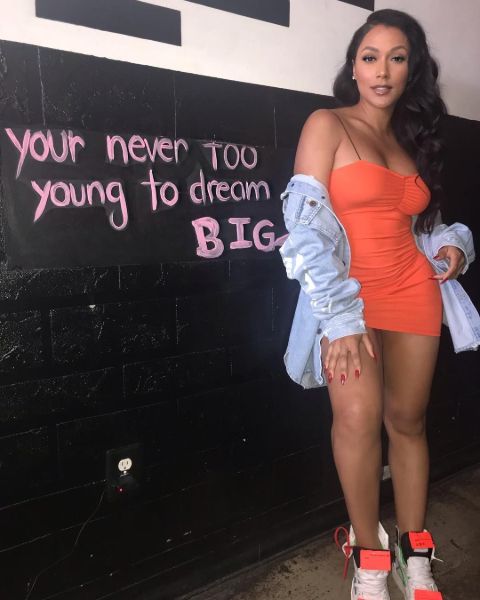 Shantel Jackson in an orange dress poses for a picture.